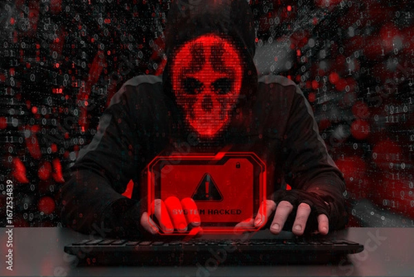 Fototapeta Masked hacker behind a computer with a red warning System hacked. Concept of cybersecurity threat, attacks on data and online systems.