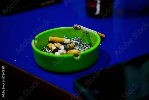 Fototapeta Cigarette and ashtray on blue background