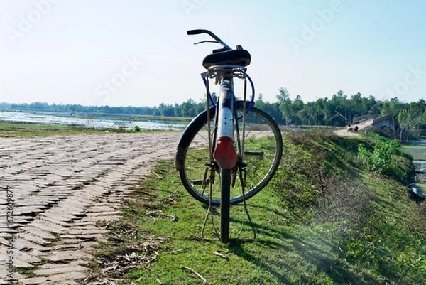 Fototapeta Bicycle on the road with green grass field background 