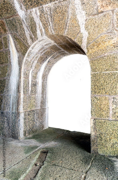 Fototapeta An old passageway with an arch built from large blocks of rustic, aged stone. Brazilian fortification, damp stains on the wall, and a damp rock floor. Isolated on a transparent background.