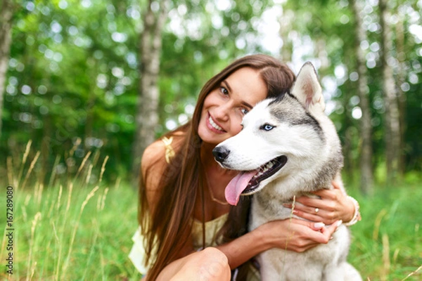 Fototapeta Happy woman  playing with her dog in the yard of the house in spring. Siberian husky.