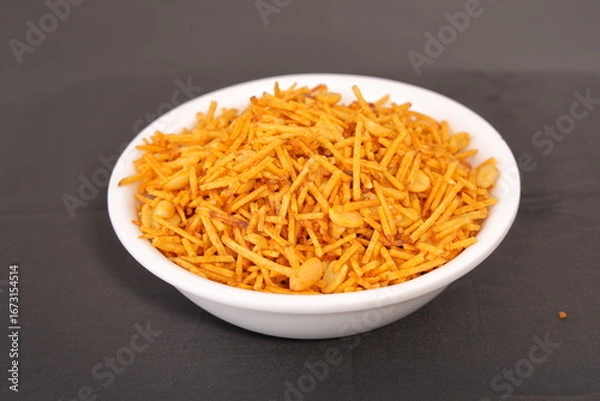 Obraz Aloo or alu chivda or chiwda. A healthy and delicious snack with fried grated potatoes with cornflower coating and nuts served in traditional bowl. A snacks for fast in Indian culture.