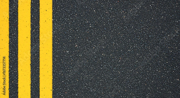 Fototapeta Close up overhead view of bright yellow double traffic lines painted on a textured dark asphalt road surface creating a bold graphic pattern