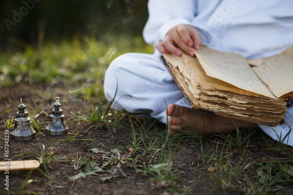 Fototapeta a boy in a kimono sits in a lotus position meditating in autumn, reading old book of wisdom