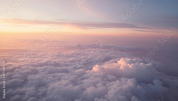 Fototapeta A breathtaking aerial view of a pastel cloudscape at sunset, with fluffy clouds in soft shades of pink, peach, lavender, and blue blending into a golden horizon. The dreamy sky creates a serene  
