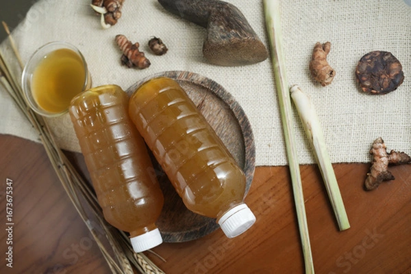 Fototapeta Plastic bottle containing fresh herbal drink with spices in a mortar. Traditional health drink made from natural ingredients. Top view (2)