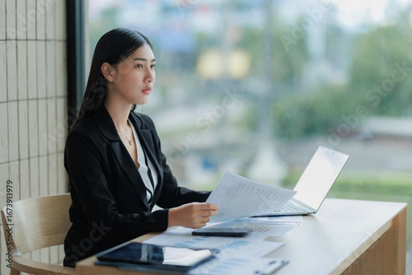 Fototapeta Asian office woman focused on computer work, typing and concentrating on business tasks.