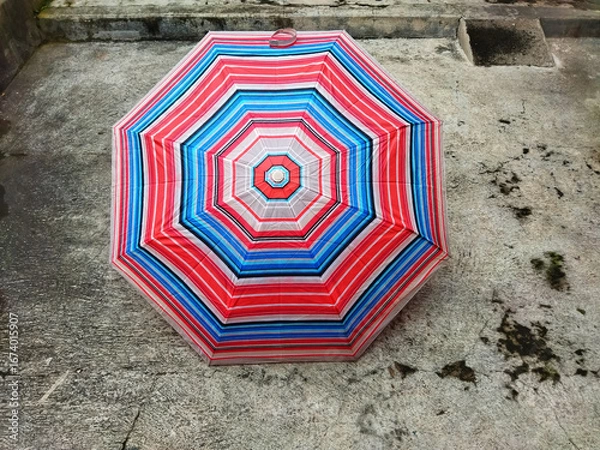Fototapeta colorful patterned umbrellas in the yard after rain. rainbow umbrella. natural background. colorful umbrella, symbol of rainy weather season. copy space. banner