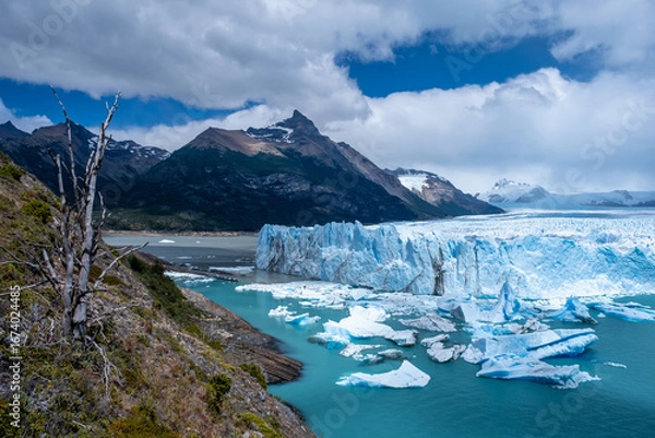Fototapeta Panoramic view of the Perito Moreno Glacier in Patagonia, Argentina, with turquoise waters, icebergs, and dramatic mountains under a cloudy sky