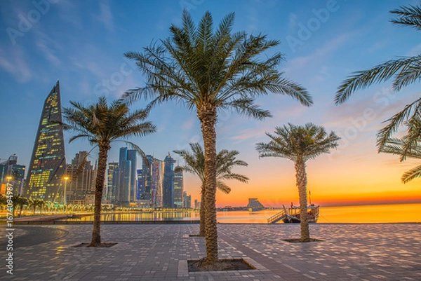 Fototapeta Doha city business downtown center panorama illuminated at sunrise, with modern skyscrapers and sea in the foreground, Qatar