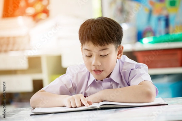 Obraz Happy asian child reading book with smile face at school