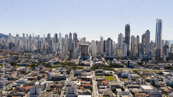 Fototapeta Aerial view from inland side of Balneário Camboriú showcasing dense skyline and modern architecture.