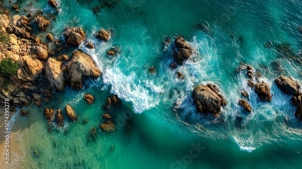 Fototapeta Aerial view of rocky shoreline meeting turquoise ocean water forming wave pattern and rugged coastal detail capturing natural beauty and seaside terrain texture