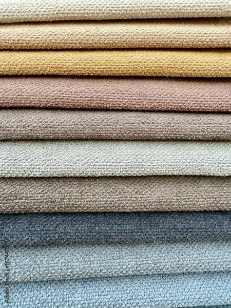 Fototapeta A vibrant display of colourful fabric pieces like towels stacked neatly on top of each other. Represents textile variety, fashion materials, and creative design resources.