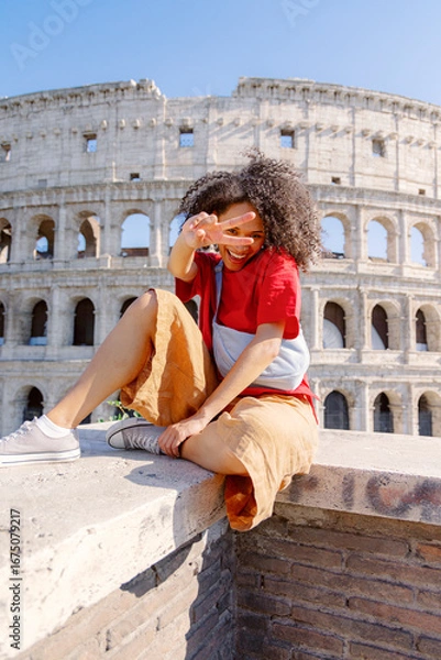 Fototapeta A cheerful child poses confidently with bright enthusiasm before the Colosseum in Rome, capturing a joyful moment in a historic setting that reflects their happiness in the bustling city