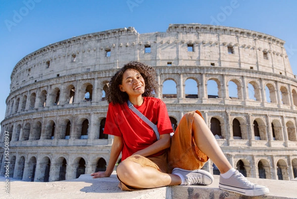 Fototapeta A very cheerful traveler poses happily in front of the iconic Colosseum in beautiful Rome, capturing the sheer joy of exploration and thrilling adventure during their memorable visit