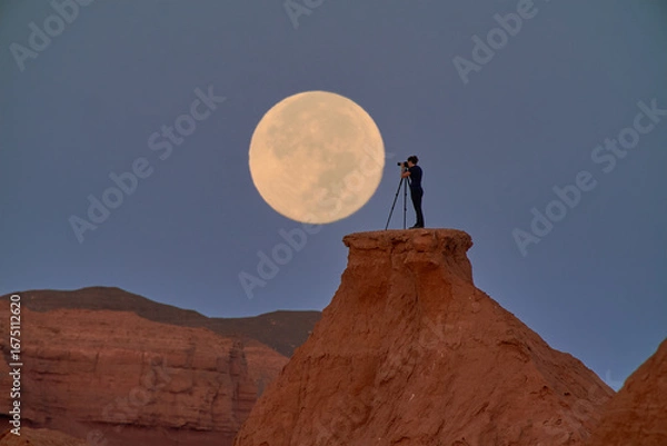 Obraz A photographer captures the full moon over a serene desert at dusk