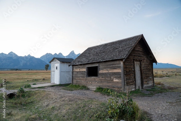 Obraz Rustic Wooden Cabin with Mountain Background in Countryside