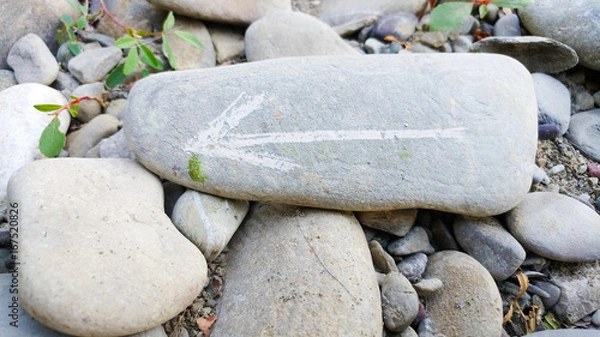 Obraz Painted arrow on stone show direction on dry rocks close to river side on stone pile