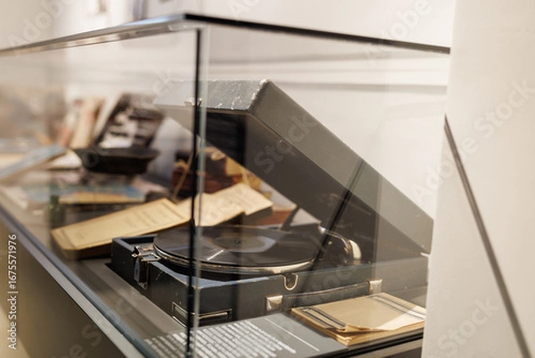 Obraz An antique gramophone in a wooden case stands in a glass display case.
