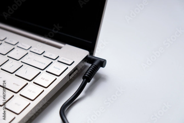 Fototapeta Charging laptop with power adapter isolated on white background