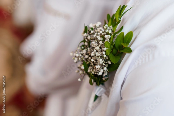 Fototapeta Wedding Boutonniere Close-Up: Delicate White Babys Breath and Greenery on Groom's Lapel, Formal Attire, Blurred Background, Soft Lighting
