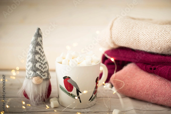 Obraz Christmas still life with robin cup filled with chocolate and marshmallows, gnome doll and string lights. Festive, cozy  background with copy space.