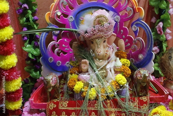 Fototapeta Ganapati festival celebration at home with a beautifully decorated Ganesh idol, flowers, lights, and traditional offerings, symbolizing devotion, prosperity, and cultural heritage in a festive atmosph