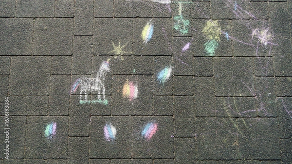 Fototapeta Colorful chalk drawings on a paved surface, including a unicorn and scattered, vibrant shapes and doodles.