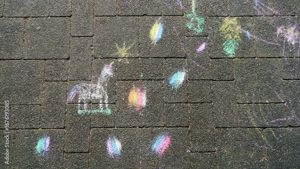 Fototapeta Colorful chalk drawings on a paved surface, including a unicorn and scattered, vibrant shapes and doodles.