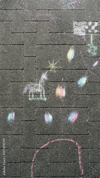 Fototapeta Colorful chalk drawings on a paved surface, including a unicorn and scattered, vibrant shapes and doodles.