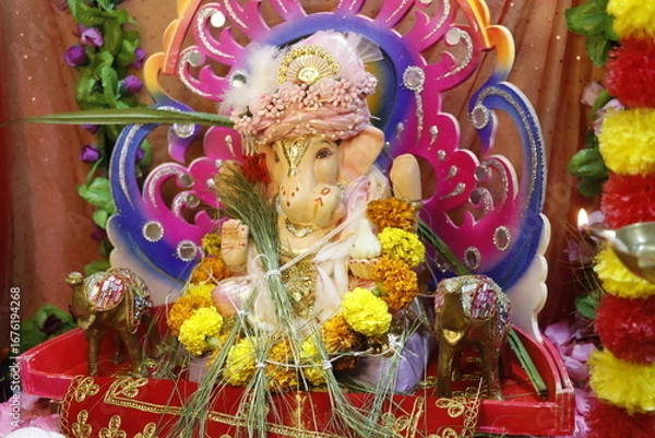 Fototapeta Ganapati festival celebration at home with a beautifully decorated Ganesh idol, flowers, lights, and traditional offerings, symbolizing devotion, prosperity, and cultural heritage in a festive atmosph