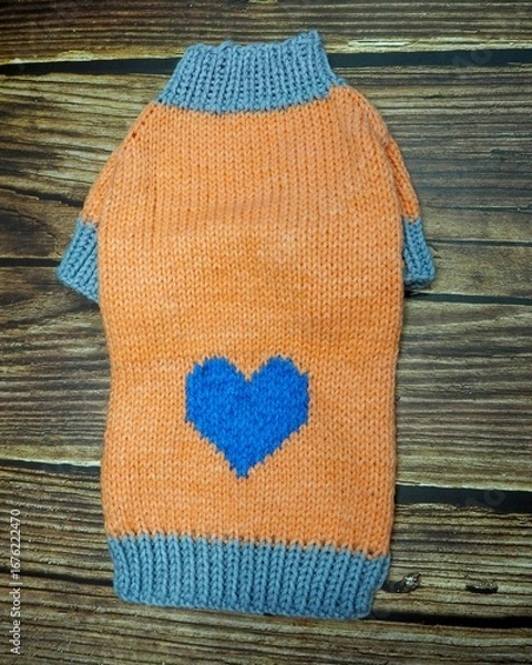 Fototapeta top view of knitted orange dog sweater with blue heart and gray rib. warm clothes for pets