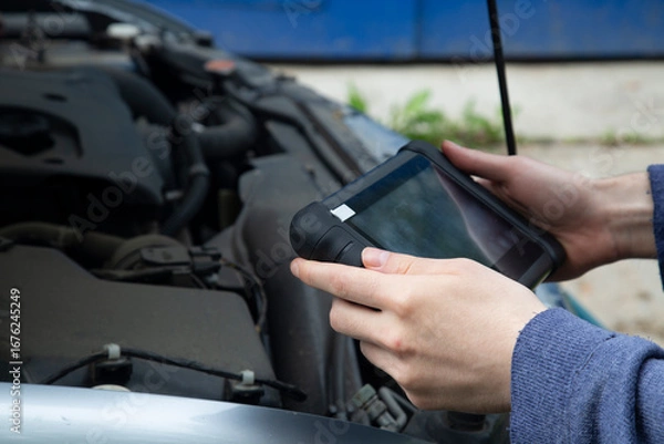 Fototapeta Car diagnostics. An auto mechanic performs car diagnostics using a scanner.