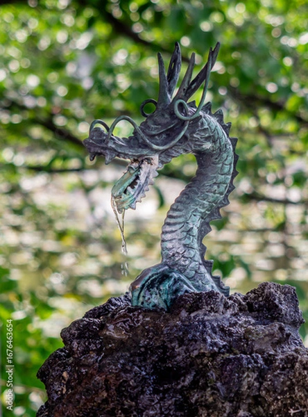Fototapeta Dragon water feature in Ueno Park with green out of focus background