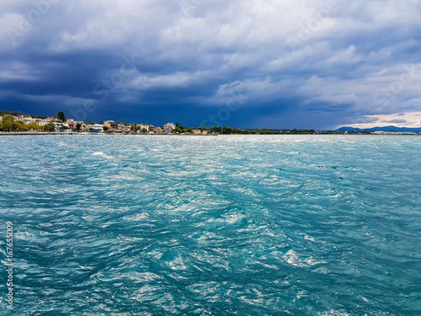Fototapeta Beautiful scenery at Oropos Greece with the village against the sea and a dramatic sky.
