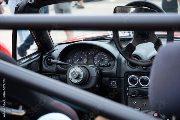 Fototapeta A closeup of the interior cockpit of a classic NB car. The JDM sports car is modified with a quick-release steering wheel and a race-spec roll bar.