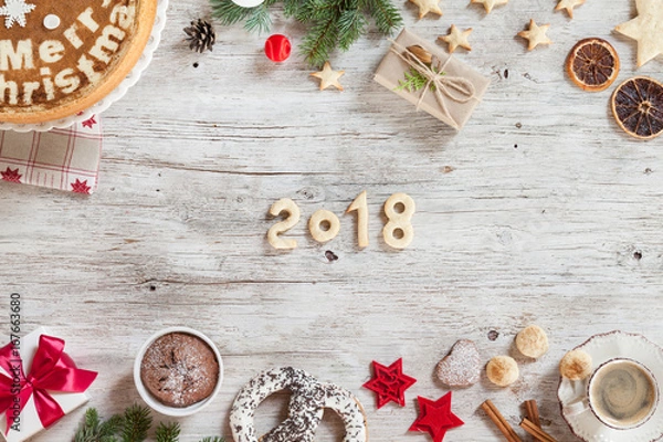 Fototapeta Composition with snowflakes, sweets, candies, cinnamon, number year 2018 on a beige wooden background. Christmass background with branches of furry spruce, cup of coffee, red christmas tree toys.