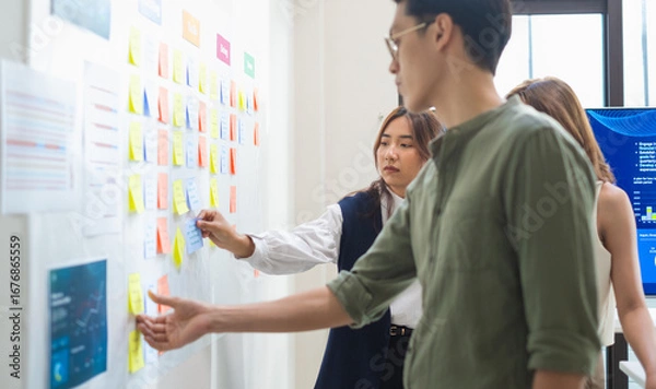 Fototapeta brainstorming session, using sticky notes on a task board (kanban) to organize ideas and workflow in a modern office