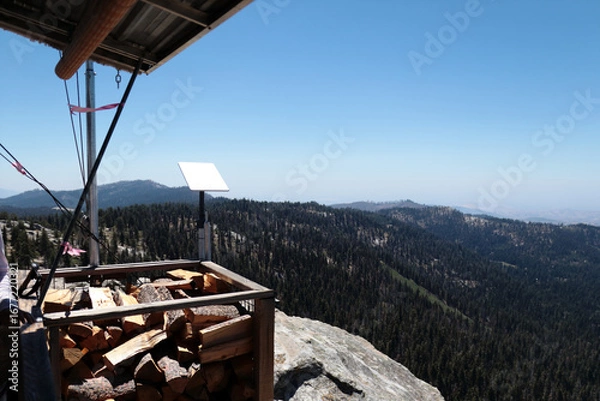 Fototapeta Split logs of firewood located near an observation tower high in the mountains