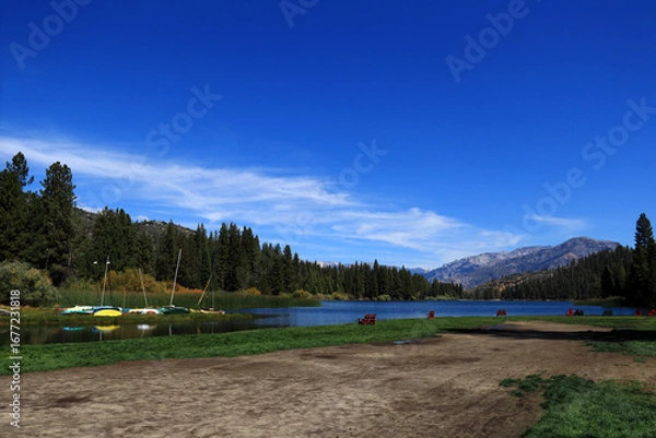 Fototapeta A tourist recreation center in the mountains. In the middle of the photo there is a small lake with yachts and sun loungers