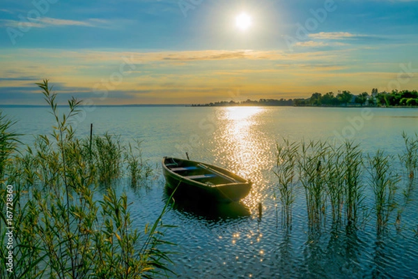 Obraz Rowing boat on lake at sunset.  Small wooden rowing boat on a calm lake at sunset.
