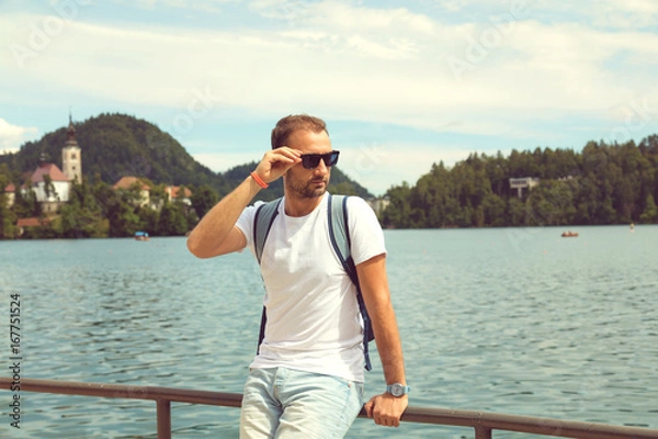Fototapeta Tourist man sitting on the lake and enjoying the view.