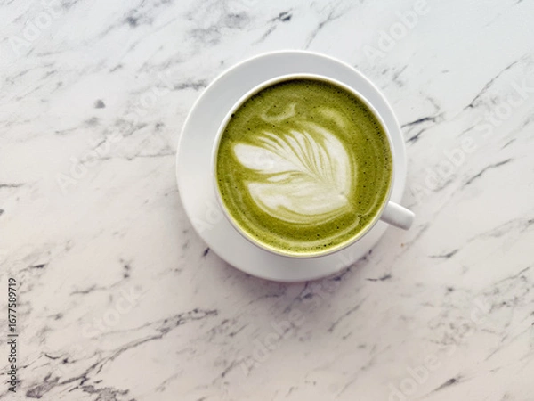 Fototapeta Top view of matcha latte with latte art on marble table. Wellness, organic beverage and cafe lifestyle