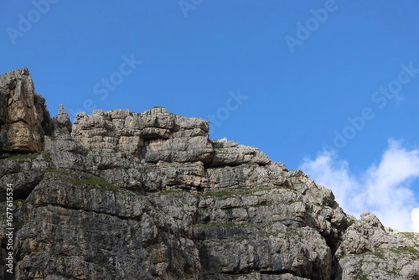 Fototapeta Trentino, Italy - July 29, 2025: Panoramic view of the majestic Piz Boe and the surrounding Dolomite peaks, with lush green valleys and scattered snow, under a clear blue sky. beautiful view to Lake b