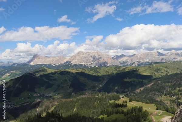 Fototapeta Trentino, Italy - July 29, 2025: Panoramic view of the majestic Piz Boe and the surrounding Dolomite peaks, with lush green valleys and scattered snow, under a clear blue sky. beautiful view to Lake b
