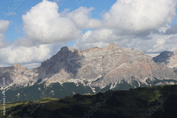 Fototapeta Trentino, Italy - July 29, 2025: Panoramic view of the majestic Piz Boe and the surrounding Dolomite peaks, with lush green valleys and scattered snow, under a clear blue sky. beautiful view to Lake b