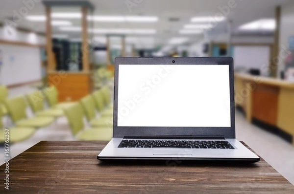 Fototapeta Laptop notebook computer with white blank screen on wooden desk with blurred view of empty chairs in clinic or hospital, heart health care and medical technology concept, selective focus, copy space