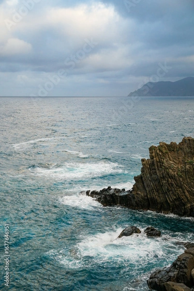 Obraz A view of sea waves crashing against a rocky cliff, with another island 