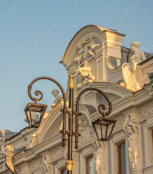 Fototapeta Lantern on the background of the facade of an ancient building with sculptures
